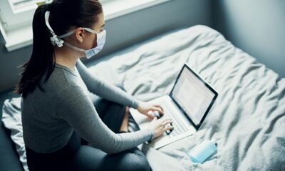 a woman wearing a mask and using a laptop